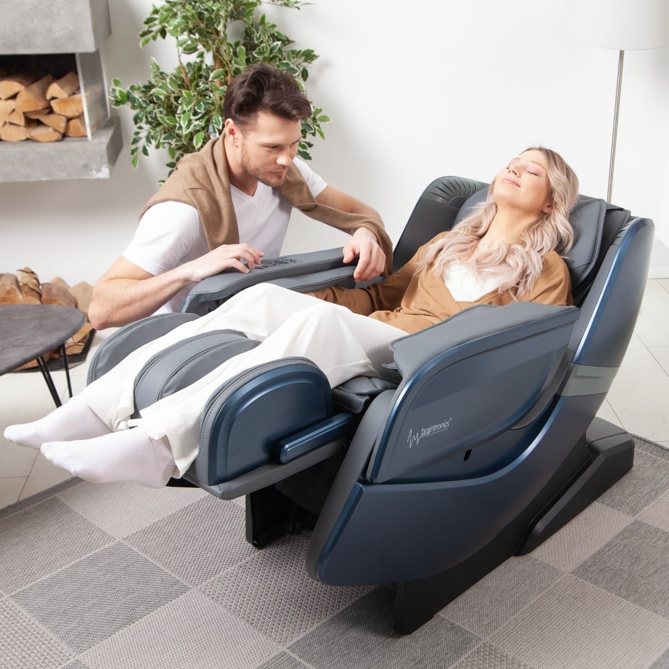 mujer tumbada en sillón de masaje Ecosonic - Azul con hombre agachado a su lado
