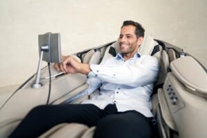 Mann im Massagesessel Casada skyliner III - khaki mit Bildschirm