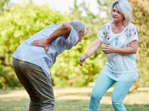 Donna che aiuta un uomo con i sintomi della lombalgia