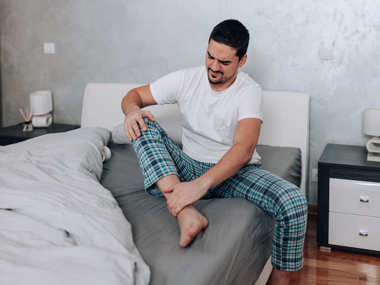 uomo in pigiama con dolori muscolari in tutto il corpo e stanco