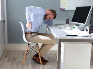 hombre en la oficina en el escritorio con dolor de espalda