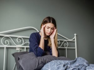 vrouw in bed die moet opstaan met hoofdpijn