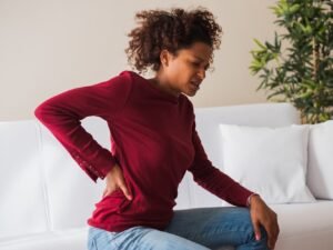 vrouw op zetel met overal spierpijn en gewrichtspijn